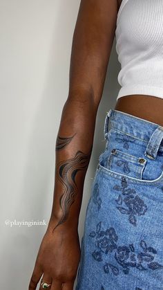 a woman with a tattoo on her arm and hand is standing in front of a white wall