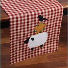 a red and white checkered table runner with a sheep on it's back