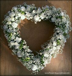 a heart shaped wreath with white flowers and baby's breath