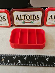 three red trays sitting on top of a table next to a measuring tape and ruler