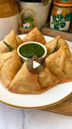 a white plate topped with pastries next to a bowl of green sauce on top of it