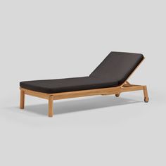 an outdoor chaise lounge chair with grey cushions and wood frame, viewed from the side