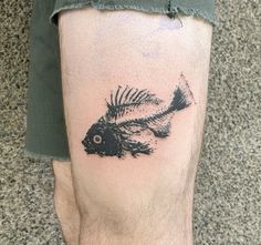 a black and white fish tattoo on the left calf area of a man's leg