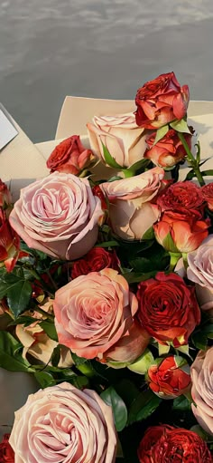 a bouquet of roses sitting on top of a table next to the ocean and water