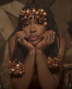 a woman with her hands on her face and beads around her neck, posing for the camera