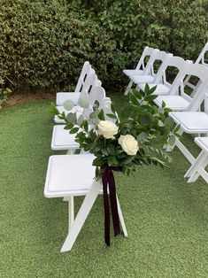 a bouquet of flowers sitting on top of a white table with chairs in the background