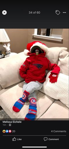 a little boy sitting on top of a couch wearing a santa hat and mittens