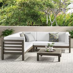 a white couch sitting on top of a patio next to a wooden table and potted plants