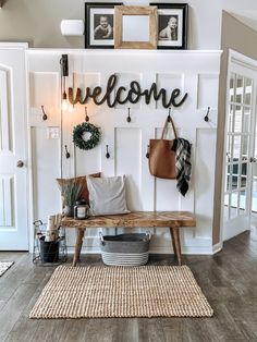 a wooden bench sitting in front of a white wall with a welcome sign on it