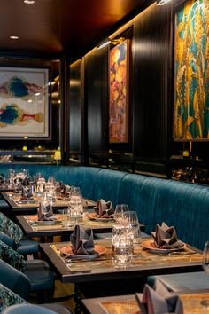 an empty restaurant with blue booths and art work on the wall behind the booth tables