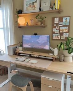 a desk with a computer on top of it and some plants in front of the monitor