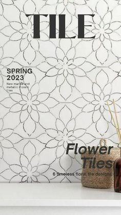 the front cover of this magazine features flowers and reeds in vases on a shelf