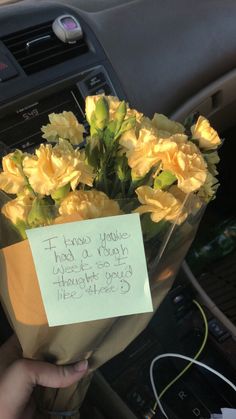 a person holding a bouquet of flowers in their hand with a note attached to it