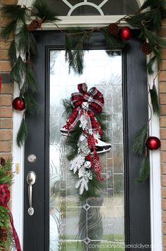 a christmas wreath is hanging on the front door with red and white ornaments around it