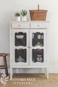 an old white cabinet with glass doors and baskets on top is shown in this image