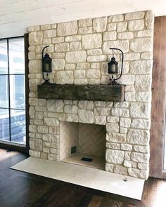 a stone fireplace with two lanterns on the mantle