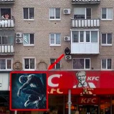 an apartment building with many windows and balconies on the top floor, next to a red sign that says kfcc