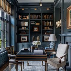 an office with blue walls and built - in bookshelves, two chairs, a desk, and a fireplace