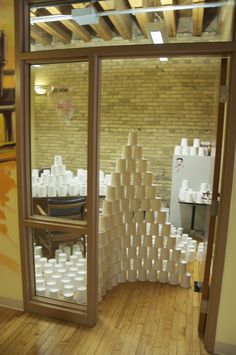 a room filled with lots of white cups on top of a hard wood floor next to a brick wall