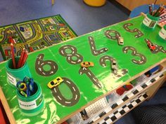 a table with cars and numbers on it in the shape of race track markers, pencils, markers, markers, pens and markers