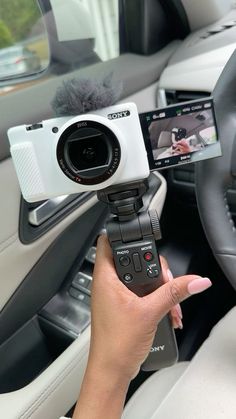 a person holding a camera in their hand while sitting in the driver's seat