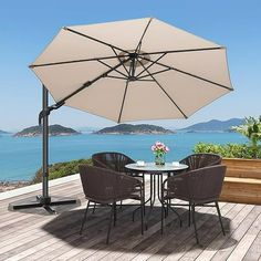 an outdoor table with chairs and an umbrella over it on a deck overlooking the ocean