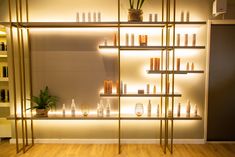 the shelves are filled with candles and vases on wooden floors in front of a white wall