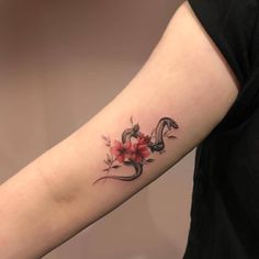 a woman's arm with a snake and flowers tattoo on the left inner arm