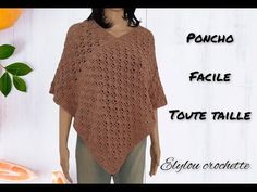 a woman wearing a brown crochet poncho is standing in front of an orange