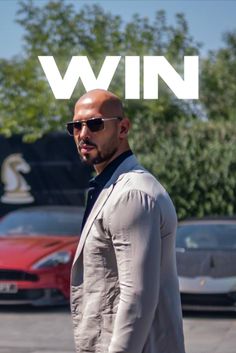 a man wearing sunglasses and a suit standing in front of a red car with the words win on it