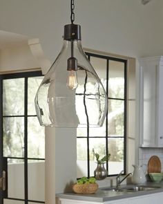 a kitchen area with a sink, stove and light hanging from the ceiling in front of windows