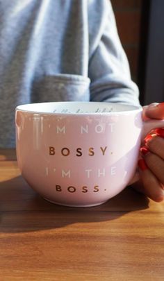 a woman holding a pink coffee cup with the words i'm not bossy, i'm the boss on it