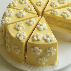 a white plate topped with a cake covered in yellow frosting and flowered decorations