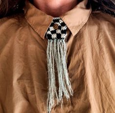 a close up of a person wearing a brown shirt with a tassel on it