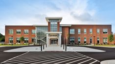 an empty parking lot in front of a large brick building with glass doors and windows