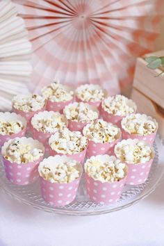 there are many cupcakes that are on the table with paper fans in the background