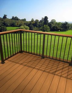 a wooden deck with railings and grass in the background