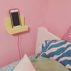 a cell phone is plugged into a wall charger in a bedroom with pink walls