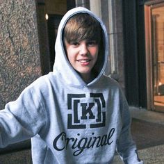 a young boy in a grey hoodie is holding his hands out to the side