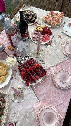 a table topped with plates and desserts next to bottles of wine on top of a table