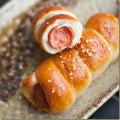 two hotdogs wrapped in bread with pepperoni on top and sesame seeds next to them