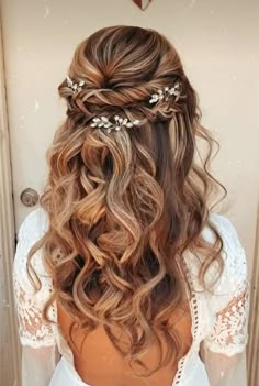 the back of a woman's head with wavy hair and flowers in her hair