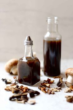 two bottles filled with liquid sitting on top of a table next to mushrooms and cloves