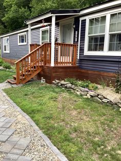 a blue house with white trim and wooden steps leading to the front door, next to a stone walkway