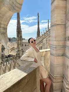 a woman is posing on the ledge of a building