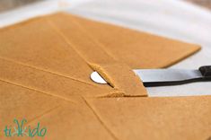 a pair of scissors cutting out some brown paper