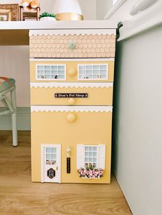 a doll house sitting on top of a wooden floor next to a desk and chair