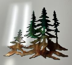 three metal trees sitting next to each other on top of a white surface with one tree cut out in the middle