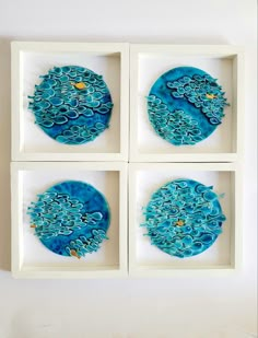 four blue artwork pieces in white frames on a wall