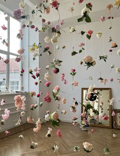 a room with flowers hanging from the ceiling and a mirror on the floor next to it